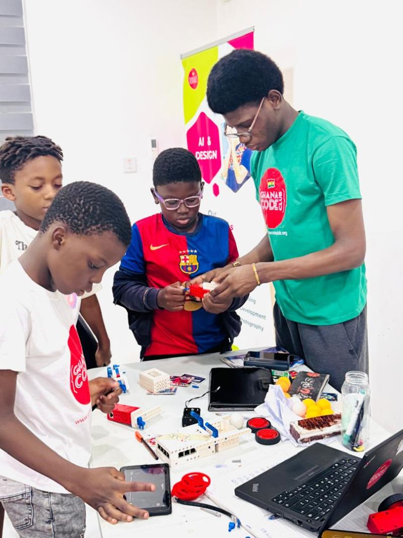 Mentoring young learners at Ghana Code Club during a robotics session, helping them build with LEGO robotics kits